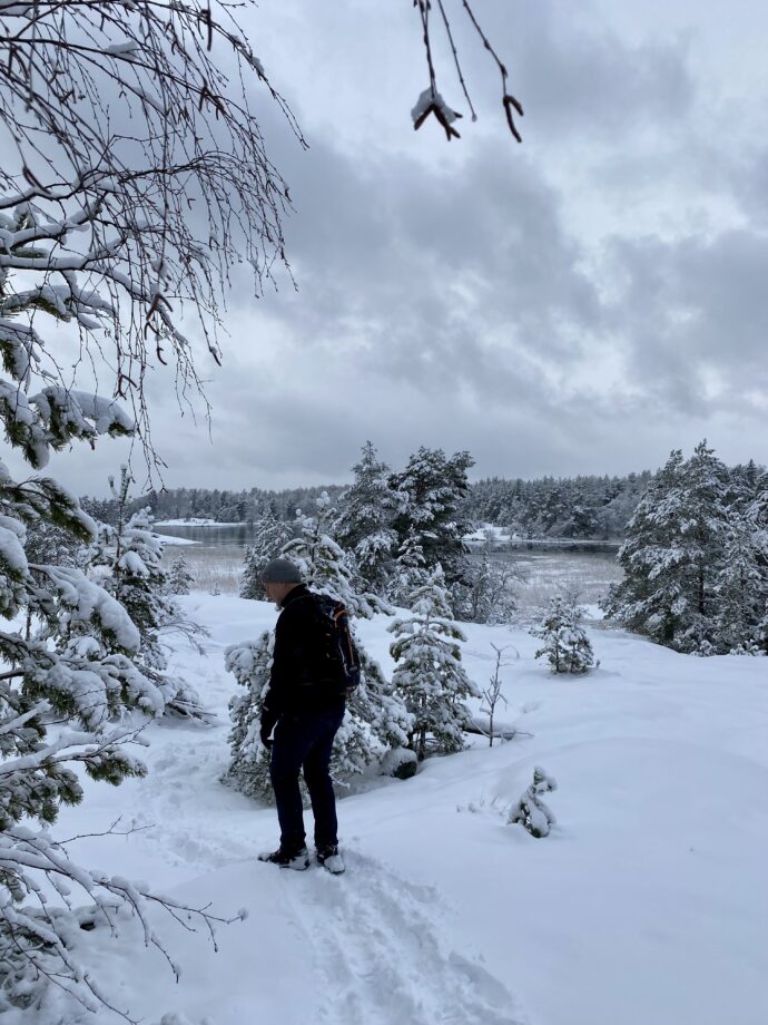 kuvassa henkilö kävelee lumisessa metsässä.