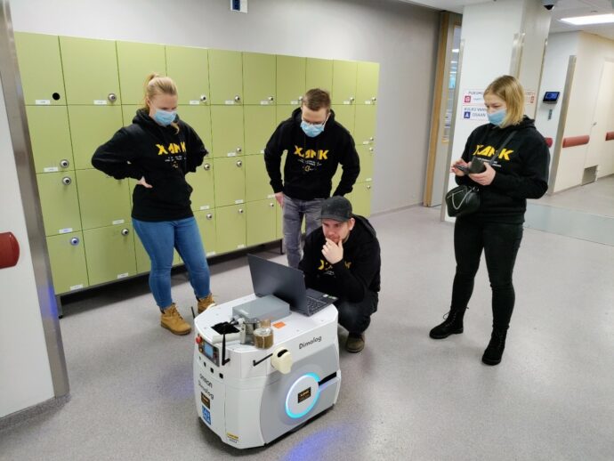 ryhmä opiskelijoita mobiilirobotin ympärillä ohjelmoimassa Omron LD60 mobiilirobottia sairaalassa. 