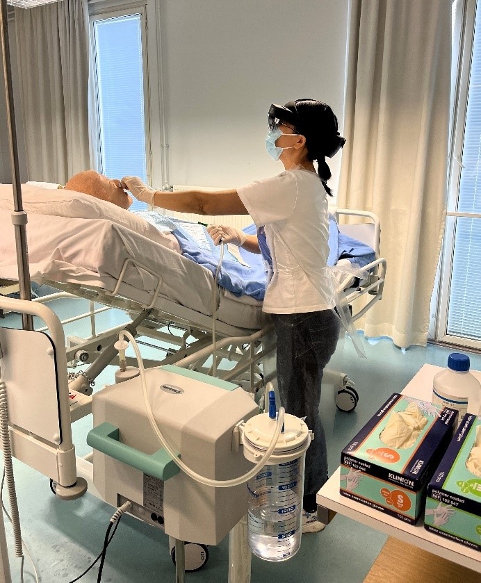 Sairaanhoitajaopiskelija harjoittelee potilaalta liman imemistä ylemmistä hengitysteistä katsoen samalla ohjeita HoloLens 2- älylaseilla, jotka ovat hänen silmillään. 