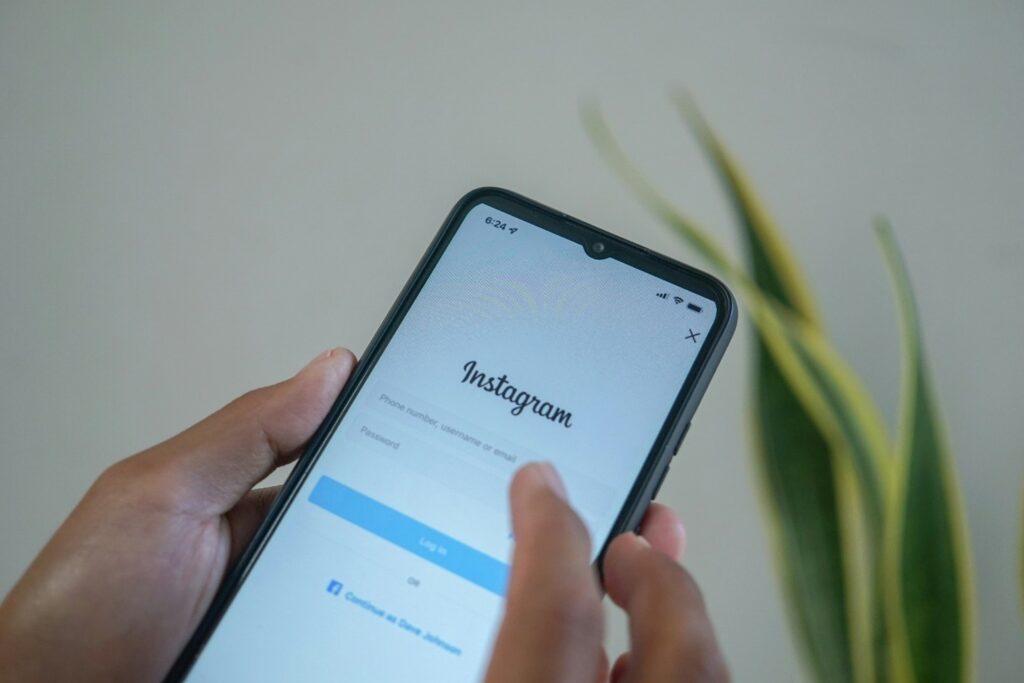 Puhelin on henkilön kädessä ja näytöllä on avoinna Instagram-sovellus.