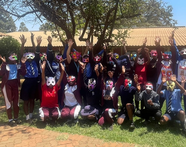 nuoria ryhmäkuvassa värikkäät naamiot päässä.