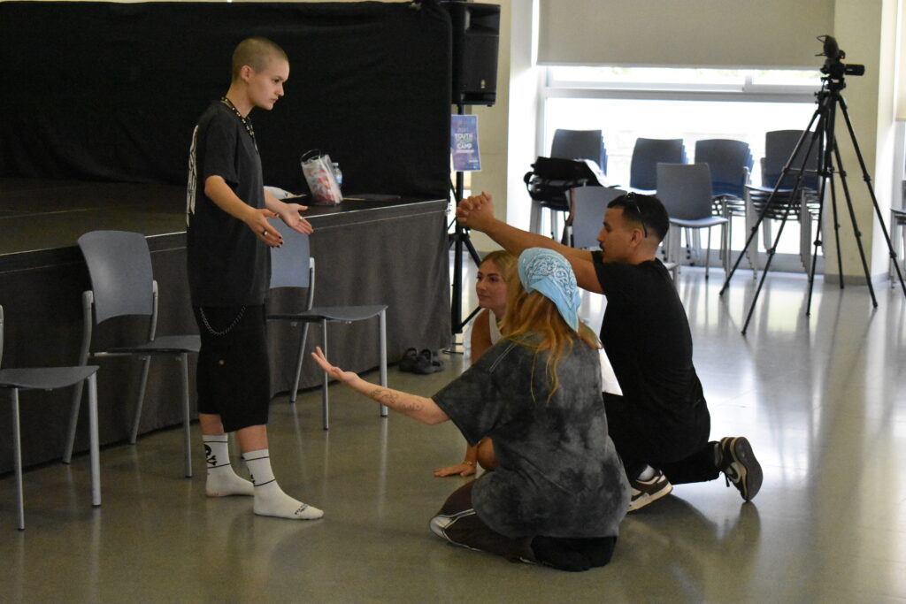 Kuvassa ilmennetään valtarakenteita; yksi osallistujista seisoo ja kolme on maassa polvillaan anomassa jotain.