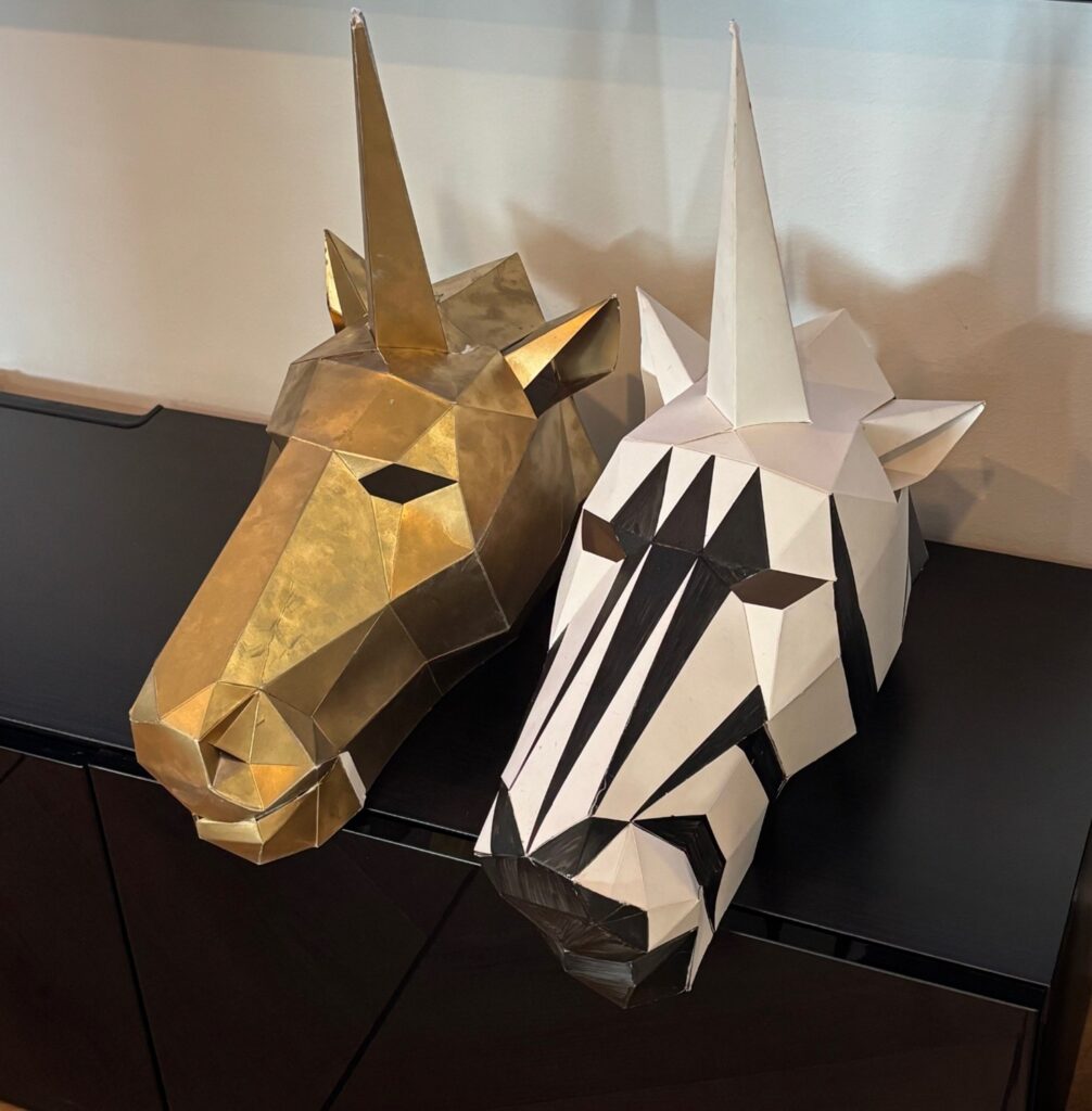 kaksi kypärää, joista toinen kultainen hevonen ja toinen seepra.