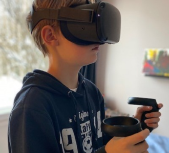 poika pelaamassa virtuaalilasit päässä. 
