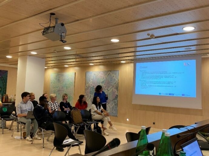 A group of people sitting in chairs in a room with a projector screen.