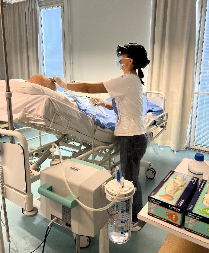 Sairaanhoitajaopiskelija harjoittelee potilaalta liman imemistä ylemmistä hengitysteistä katsoen samalla ohjeita HoloLens 2- älylaseilla, jotka ovat hänen silmillään.