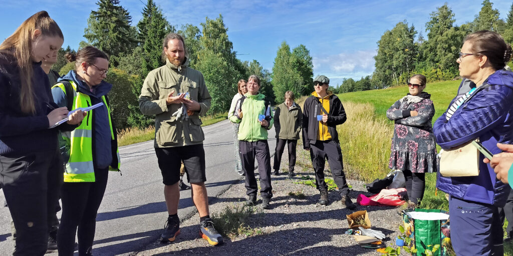  Ryhmä ihmisiä kuuntelee perusteita niittykasvien siementen keräämisestä, joista Jere Nieminen, Tuleva Luonto Oy:n perustaja kertoo.